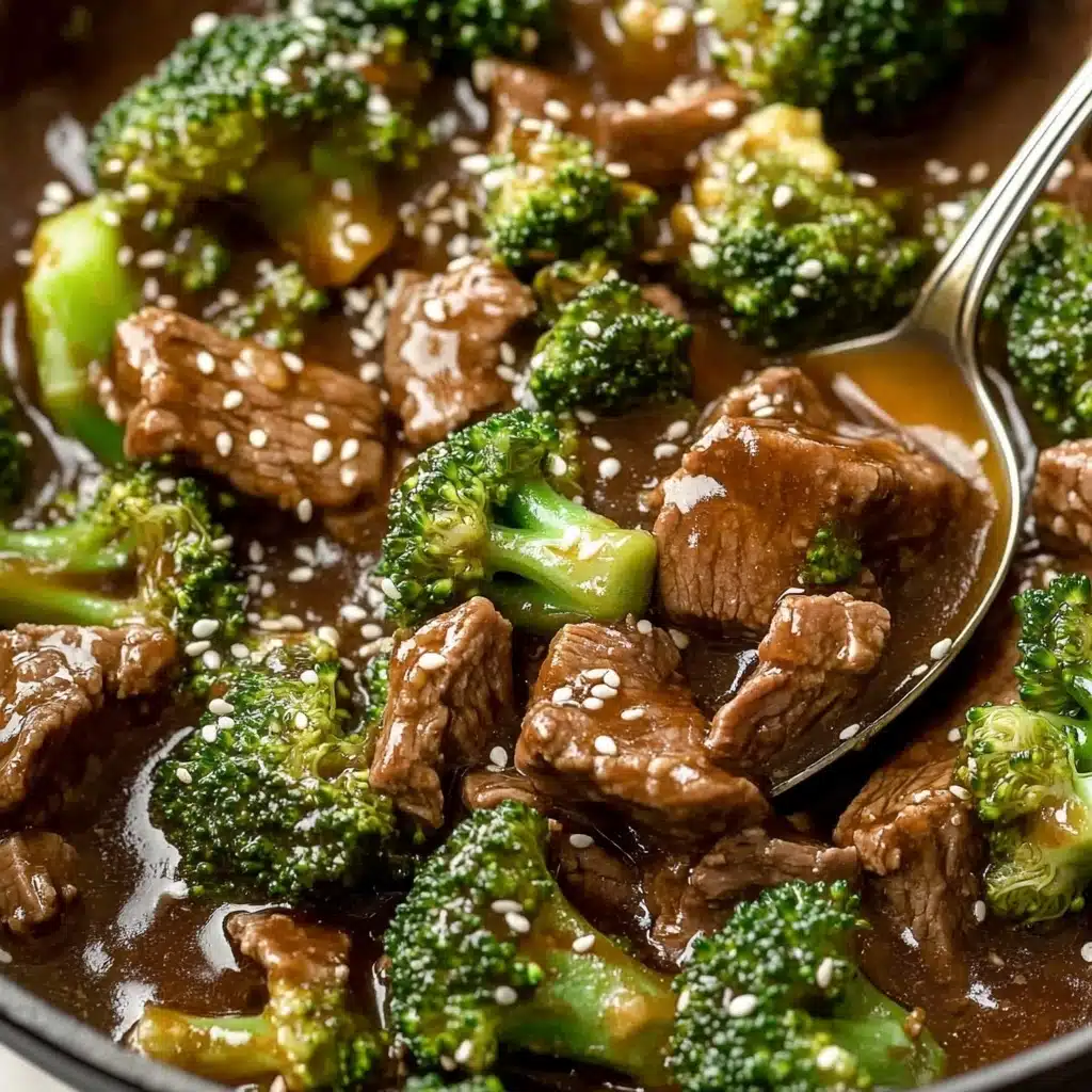 Chinese Beef and Broccoli, Chinese beef and broccoli stir-fry, beef and broccoli recipe, Chinese stir-fry recipes, quick beef stir-fry A close-up view of a dish with layers of green broccoli florets and dark brown pieces of beef mixed together in a thick, glossy brown sauce. The dish is sprinkled with small white sesame seeds, adding texture on top. A metal spoon is partially shown in the mix, scooping some broccoli and beef. The background features a white marbled texture.