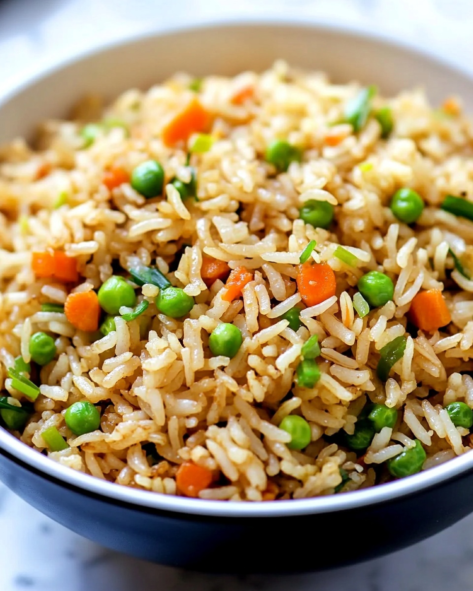 A close-up view of a bowl filled with fried rice showing a mix of long grains of light golden brown rice scattered with small bright green sliced spring onions and tiny pieces of orange carrot. The rice looks fluffy with a slight shine and is mixed evenly with the vegetables, all inside a white bowl. The background shows a soft focus and a white marbled surface beneath the bowl. photo taken with an iphone --ar 4:5 --v 6.1