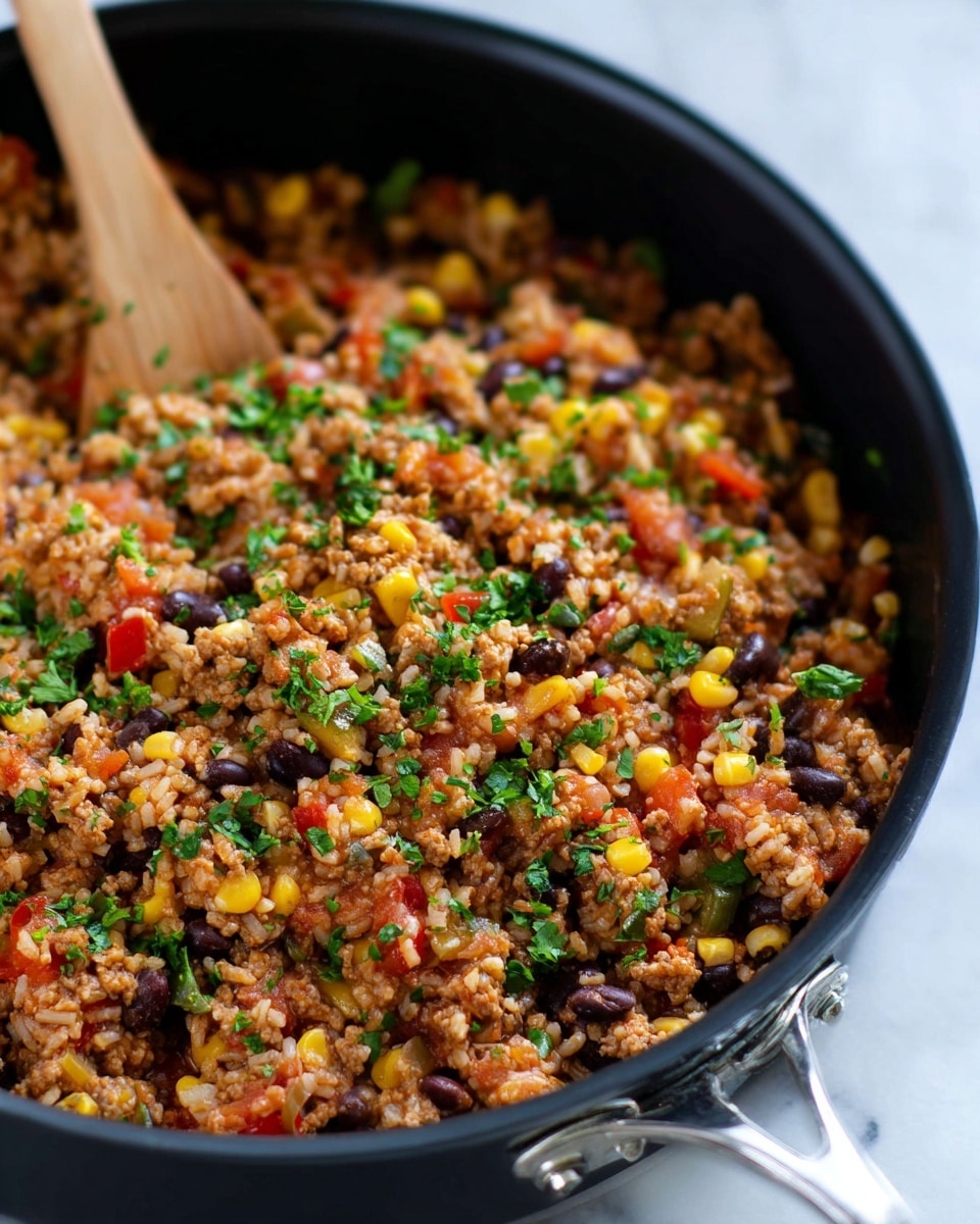 In a black pan with silver handles, a colorful cooked rice dish is shown. It has three main layers mixed together: brown cooked ground meat, yellow corn kernels, and black beans, along with chopped onions and small red pepper pieces. Bright green chopped herbs sprinkle all over the dish. The mix looks moist and chunky, with a wooden spoon partly visible stirring the food. The background is a white marbled texture photo taken with an iphone --ar 4:5 --v 7
