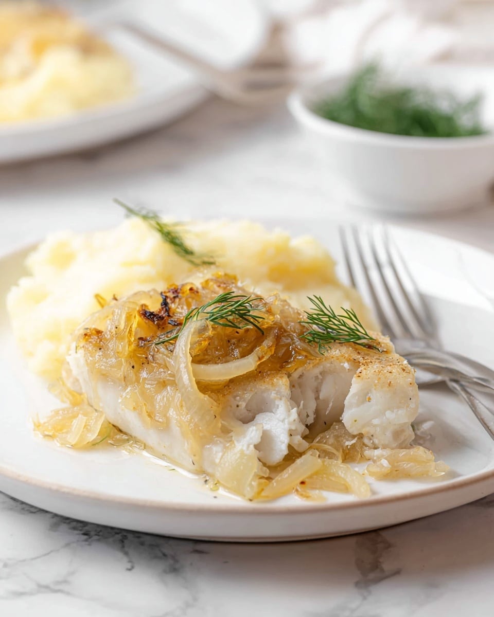 A white plate with a piece of cooked white fish topped with a layer of golden brown cooked onions and small green dill leaves, showing flaky texture inside where a bite is taken. Next to the fish are smooth, creamy mashed potatoes in pale yellow, and a small portion of cooked onions in light golden color. A silver fork rests on the plate background. The surface beneath is white marbled texture. In the blurred background, there is a small white bowl with green dill sprigs and another white plate. Photo taken with an iphone --ar 4:5 --v 7