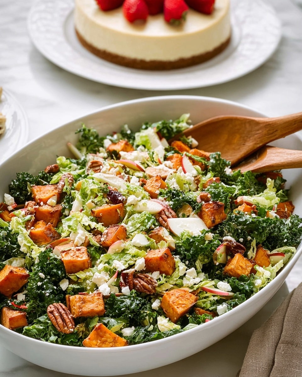 A large white oval bowl sits on a white marbled surface filled with a fresh salad. The salad has three main layers visible: a bottom layer of dark green kale leaves and lighter green shredded Brussels sprouts, a middle layer of bright orange cubes of roasted sweet potato, and a top layer of small white crumbles of cheese and small chunks of pale green and red apple pieces mixed throughout. There are also scattered pecans adding texture. A wooden spoon rests in the bowl, ready to serve. In the blurred background, there is a white plate with a cheesecake garnished with a few strawberries. Photo taken with an iphone --ar 4:5 --v 7