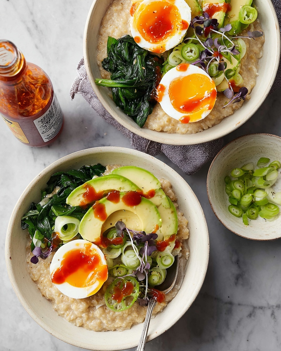 A light gray bowl holds a base layer of thick, creamy oatmeal with a soft, slightly lumpy texture filling the entire bottom. On top, there are bright green avocado slices arranged in a small stack with smooth, fresh flesh visible. Beside the avocado, vibrant sautéed spinach with a shiny, slightly wet look is placed near the edge of the bowl. Two halves of a soft-boiled egg with bright orange yolks and firm white edges sit next to the spinach, sprinkled lightly with black pepper. Small green onion rings and dark purple microgreens scatter over the eggs and avocado, adding contrast. Dots of red sauce are drizzled sparingly over the spinach, avocado, and eggs. A silver spoon rests inside the bowl on the left side. The bowl is placed on a white marbled surface. photo taken with an iphone --ar 4:5 --v 7
