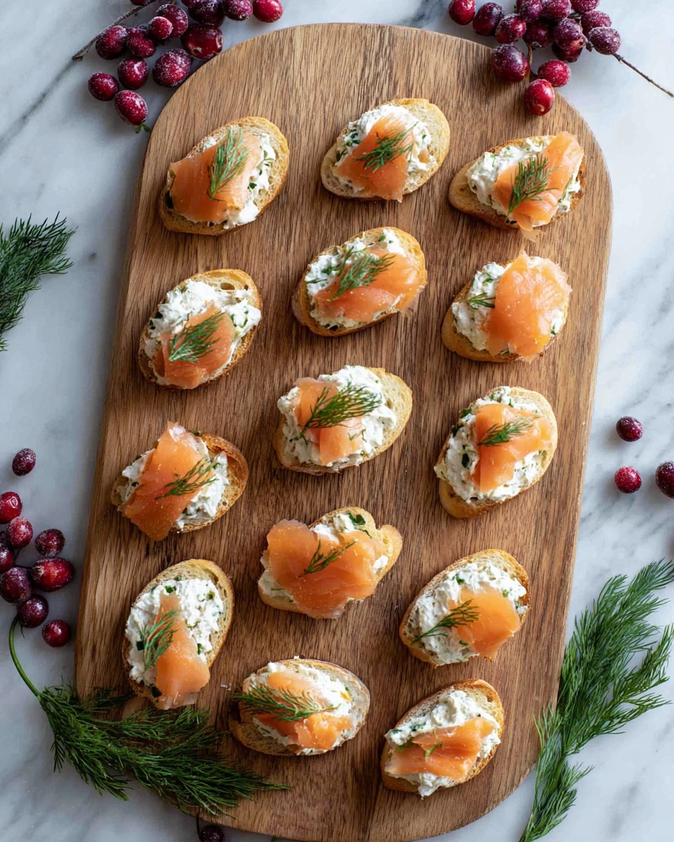 A wooden board with 14 small toasted bread pieces arranged across it, each topped with a creamy white spread mixed with green herbs, a thin slice of light orange smoked salmon, and a small sprig of fresh green dill on top. The board rests on a white marbled surface with fresh dark red cranberries placed in clusters at the top left and bottom right corners and some fresh dill sprigs scattered around. Photo taken with an iphone --ar 4:5 --v 7