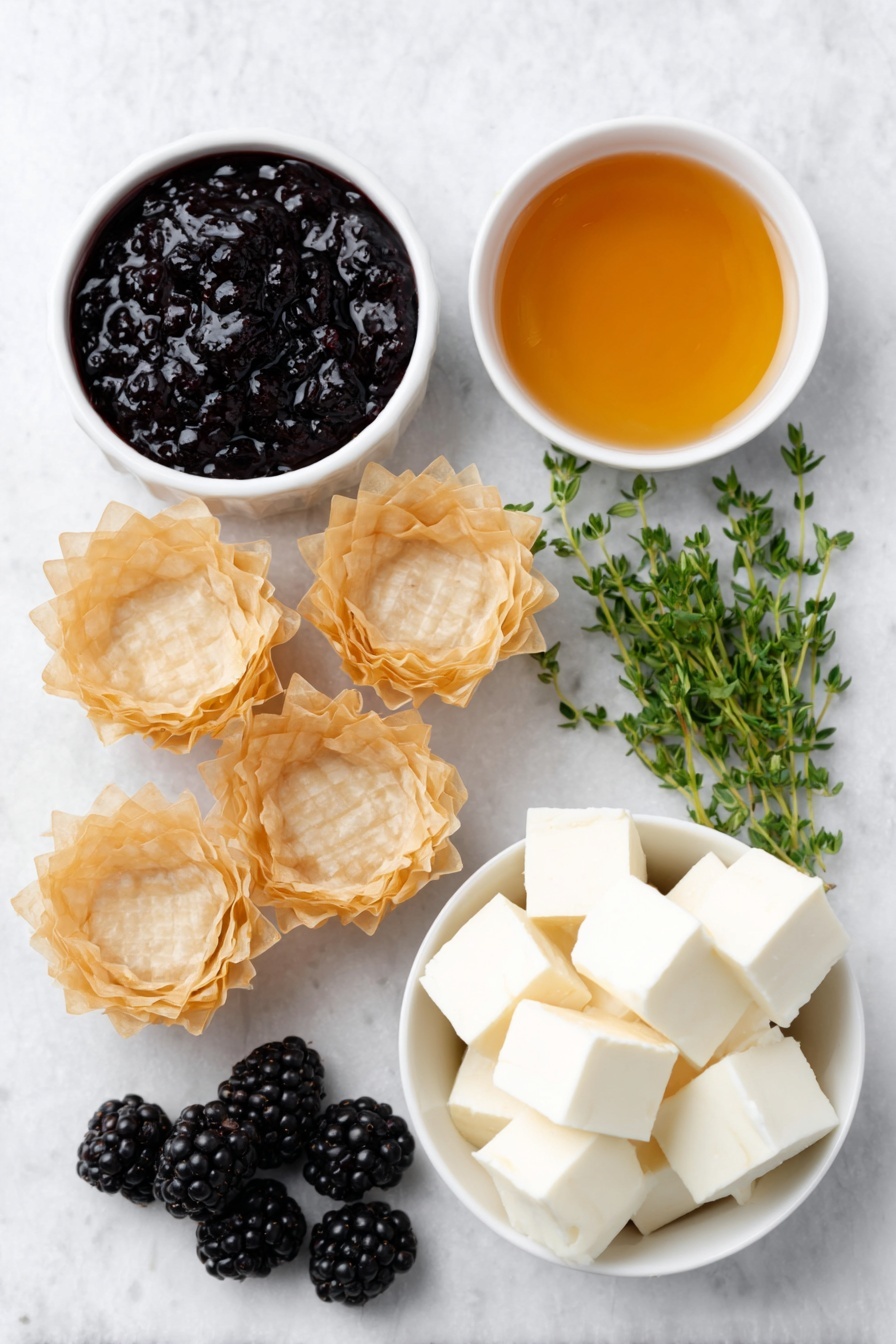 Flat lay of fresh golden mini phyllo shells arranged neatly, a small white ceramic bowl with glossy deep purple blackberry jam, another small white bowl filled with clear golden honey, creamy pale off-white cubes of brie cheese without rind, a handful of plump fresh blackberries with a rich dark purple hue, and a few sprigs of vibrant green fresh thyme artfully placed, all ingredients balanced symmetrically and naturally placed on a clean white marble surface, soft natural light, photo taken with an iPhone, professional food photography style, fresh ingredients, white ceramic bowls, no bottles, no duplicates, no utensils, no packaging --ar 2:3 --v 7 --p m7354615311229779997 - Blackberry Brie Phyllo Cups, blackberry brie appetizer, easy party appetizers, fruit and cheese bites, no-bake finger foods