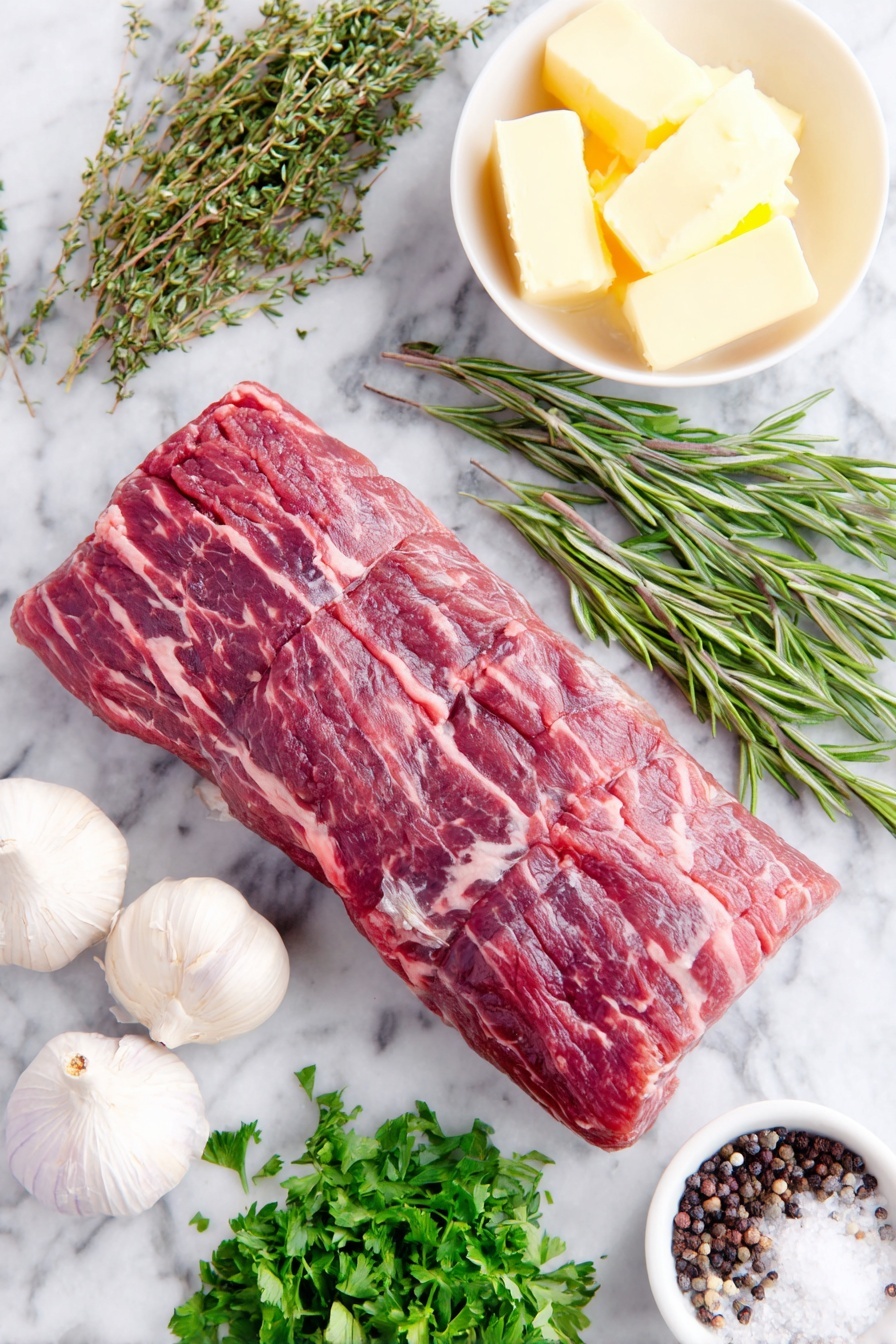Flat lay of a whole trimmed beef tenderloin roast with a rich red color and fine marbling, three whole uncracked garlic cloves with smooth white skins, a small heap of fresh flat-leaf parsley sprigs, fresh rosemary sprigs with needle-like leaves, fresh oregano sprigs with small green leaves, a few whole black peppercorns scattered naturally, a small white ceramic bowl holding softened pale yellow butter, a small white bowl with dark glossy balsamic vinegar, a small white bowl of thick Worcestershire sauce with a deep brown hue, and a small pile of coarse sea salt crystals, all arranged symmetrically with perfect balance, placed on a clean white marble surface, soft natural light, photo taken with an iPhone, professional food photography style, fresh ingredients, white ceramic bowls, no bottles, no duplicates, no utensils, no packaging --ar 2:3 --v 7 --p m7354615311229779997 - Oven-Roasted Beef Tenderloin with Garlic Butter, beef tenderloin recipe, roasted beef main dish, garlic butter beef, easy elegant beef roast