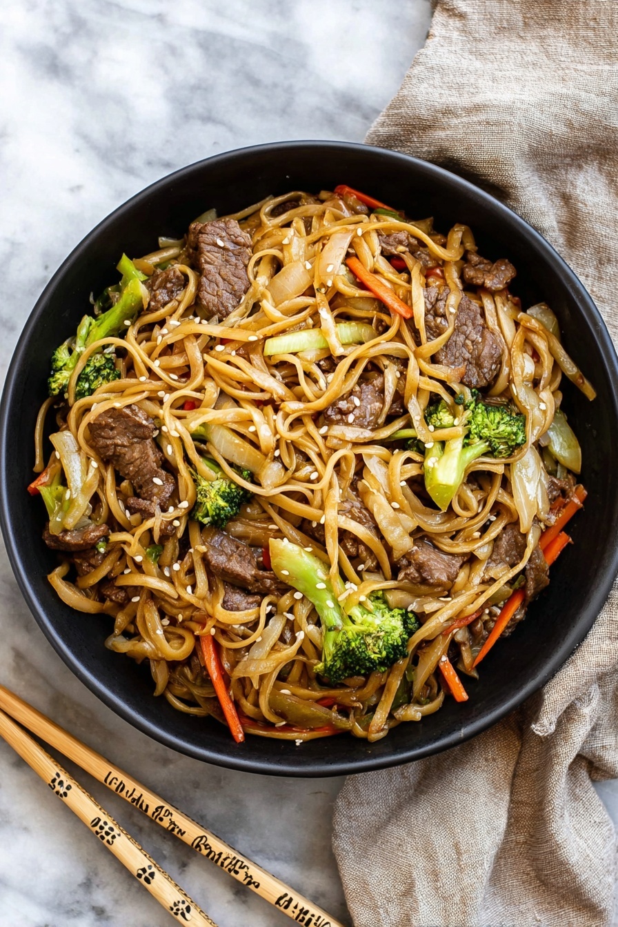 A black bowl filled with stir-fried noodles mixed with pieces of beef, bright green broccoli florets, thin orange carrot strips, and light brown cooked onions, all coated in a light sauce giving a slight shine; the noodles are long and a pale tan color, twisting through the vegetables and meat, garnished with small white sesame seeds. The bowl sits on a white marbled surface next to a pair of light wooden chopsticks decorated with simple patterns, and a beige cloth napkin is casually placed nearby. photo taken with an iphone --ar 2:3 --v 7 - Easy Beef Lo Mein, beef lo mein recipe, quick beef noodle stir-fry, simple Asian noodles, fast weeknight dinner ideas